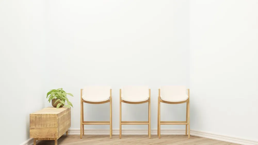 Three pale wooden chairs against a white wall
