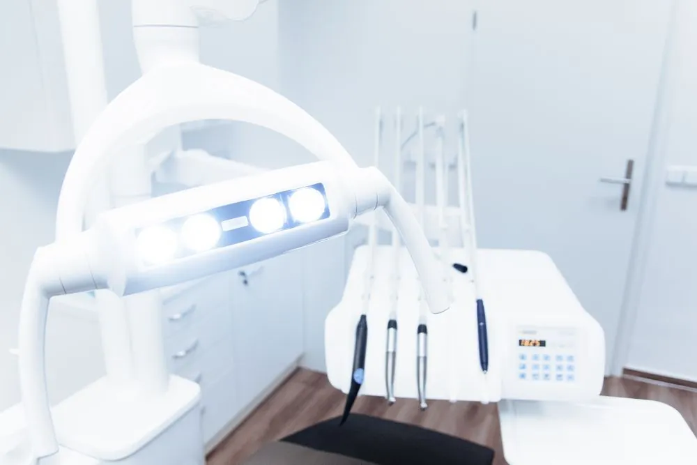 A dental chair and overhead light in an empty treatment room