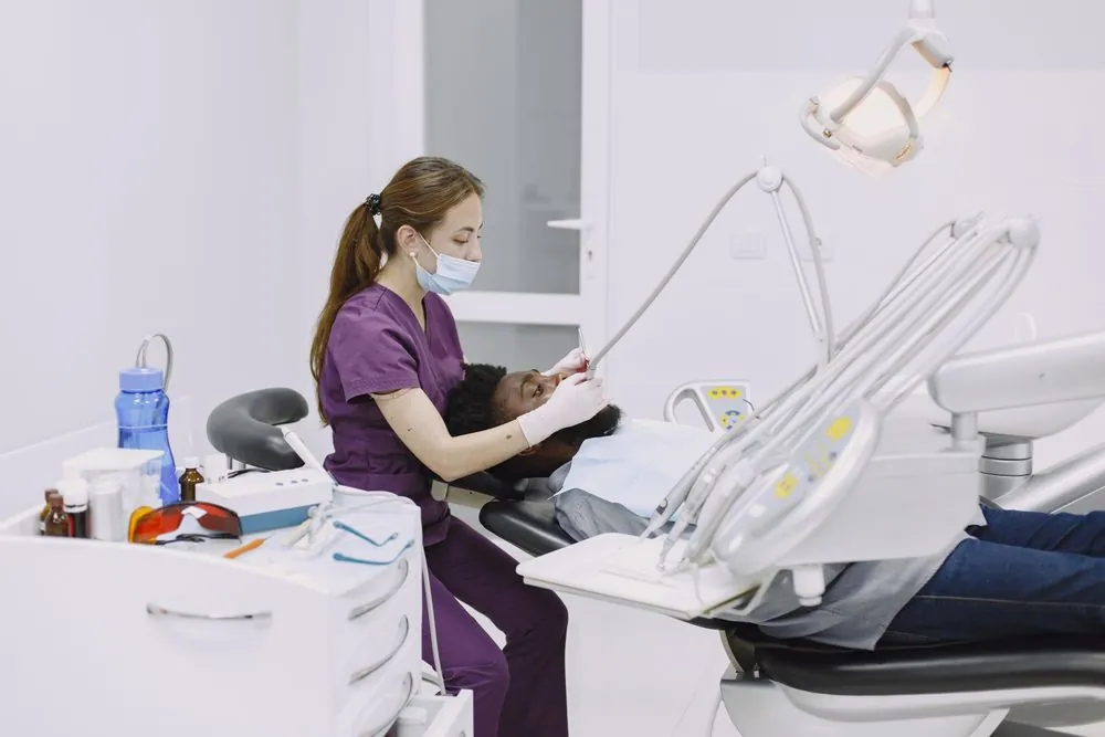 A dentist in purple scrubs working with a child in the chair